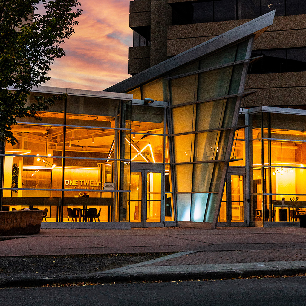 Sunset shot of One Twelve Campus building showing the interior hall from outside.